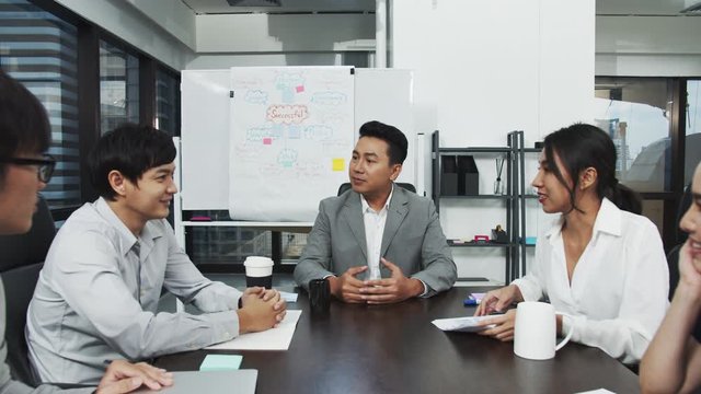 4K UHD Slow motion : Millennial asian businessman or leader manager discussion and talking with team in conference meeting room at modern office. Asian teamwork working together follow up them work.
