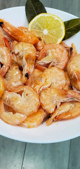 Shrimp on a white plate with lemon. Seafood. Shrimp on a plate, isolated on a gray background.
