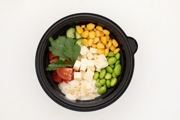 Top view of bowl of fresh beans and vegetables with tofu and sauce poke isolated on white background