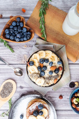 rustic Breakfast pancakes on a plate with blueberries and oatmeal with banana and nuts