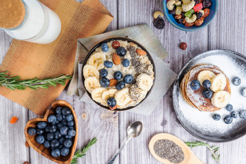 rustic Breakfast pancakes on a plate with blueberries and oatmeal with banana and nuts