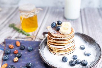 rustic Breakfast pancakes on a dark plate with blueberries and honey - 308900454