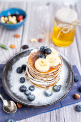 rustic Breakfast pancakes on a dark plate with blueberries and honey