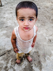 closeup of a poor staring hungry orphan boy in a refugee camp with sad expression on his face and...