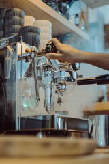 Barista steams with coffee maker in cafe