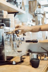 Barista steams with coffee maker in cafe