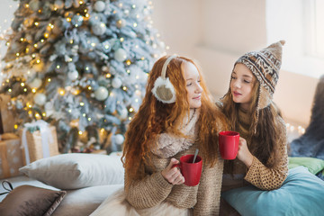 Two pretty little girls under new year tree in scandinavian christmas decorated interior
