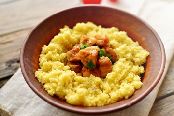 Couscous in a clay plate on a wooden background with linen textiles. Couscous with meat. Photo of food.