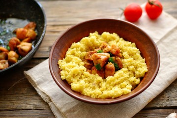 Couscous in a clay plate on a wooden background with linen textiles. Couscous with meat. Photo of food.