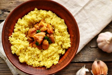 Couscous in a clay plate on a wooden background with linen textiles. Couscous with meat. Photo of food.