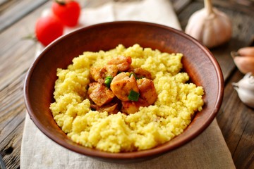 Couscous in a clay plate on a wooden background with linen textiles. Couscous with meat. Photo of food.