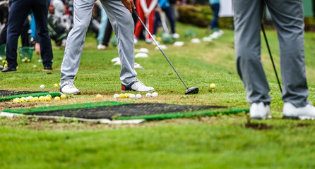 Golfer legs at golf tournament practice swing with driver.