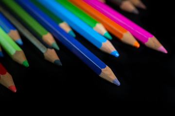 .GROUP OF COLORED PENCILS ALIGNED ON BLACK BLACKGROUND