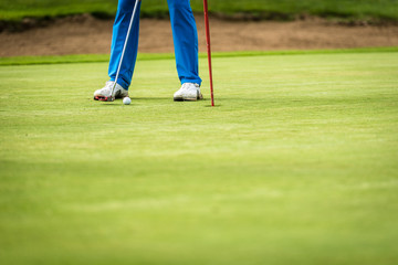 Golfer legs at golf tournament practice swing with golf club.