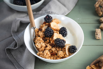 Tasty granola with yogurt in bowl on wooden table