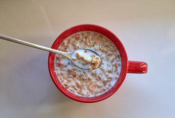 Muesli in red ceramic cup on the white table. View from top.