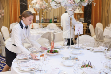Waiters set the tables in the restaurant for the banquet