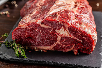 Raw meat. Beef tenderloin, neck lies on a black board, next to a knife and knife sharpener. closeup. background image. copy space