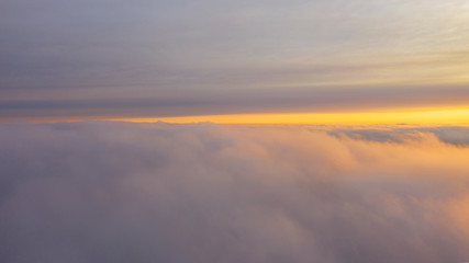 Aerial view White clouds in blue sky. Top view. View from drone. Aerial bird's eye view. Aerial top view cloudscape. Texture of clouds. View from above. Sunrise or sunset over clouds