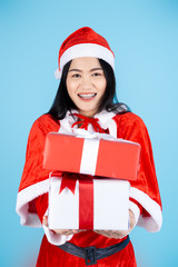 Happy Asian woman in Santa Claus costume holding Christmas gift box on blue background.