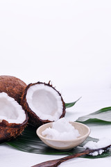 Coconuts, oil and palm leaves on a white wooden background. Natural cosmetics and healthy nutrition...