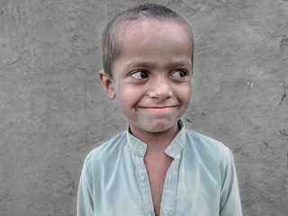 a poor smiling boy in a village wearing recycled used clothes