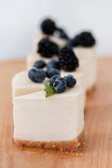 slices of classic cheesecake decorated with berries on a wooden board