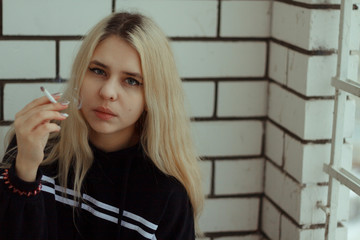 A young woman in a black sweater with white hair stands on the balcony against the background of...