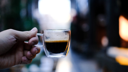 Transparent glass cup of coffee in the hand. Coffee in a cafe. 