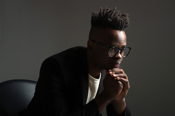 handsome african man in black suit on gray background
