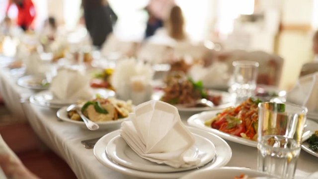 Beautifully served banquet table with different food snacks and appetizers in the sun on corporate christmas birthday party event or wedding celebration. Decorated catering in white interior.