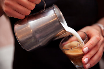 Barista pours milk into a cup of coffee