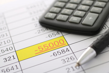 数字の統計と計算機と筆記用具と赤字