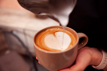 Barista pours milk into a cup of coffee