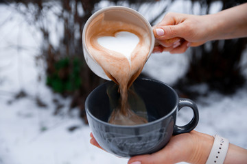Barista pours milk from one cup to another