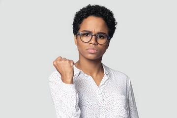 Angry african american serious girl clenching fist, demonstrating power.