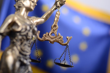 Scales of Justice, Justitia, Lady Justice in front of the European Union flag in the background.