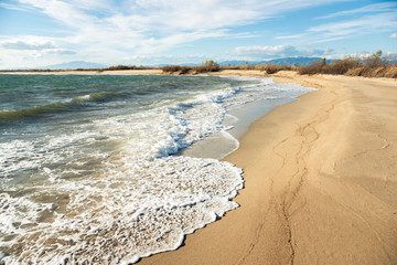 Scenic view on sandy beach with waves and sea at daytime.