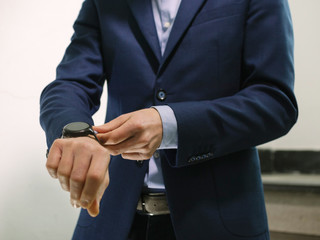 Man in blue blazer jacket with watch walking down stairs while fixing sleeve