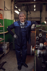 Naklejka na ściany i meble Portrait of manual worker standing in work uniform and looking at camera in the factory