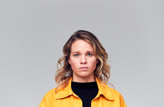 Studio Portrait Of Worried Young Woman Looking At Camera