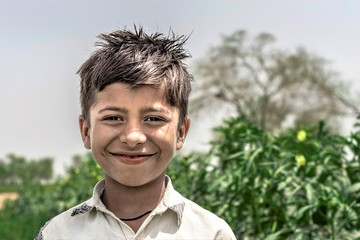 an Asian poor child is smiling in an open rural area 