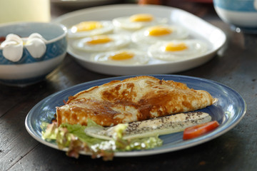 wooden table is covered with healthy variety of natural food, banana porridge, scrambled eggs, omelet with vegetables, coconut, dragon's eye.