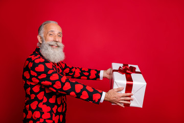 Profile side view portrait of nice attractive cheerful cheery glad white-haired man cherub holding in hands giving gift every year tradition isolated on bright vivid shine vibrant red color background