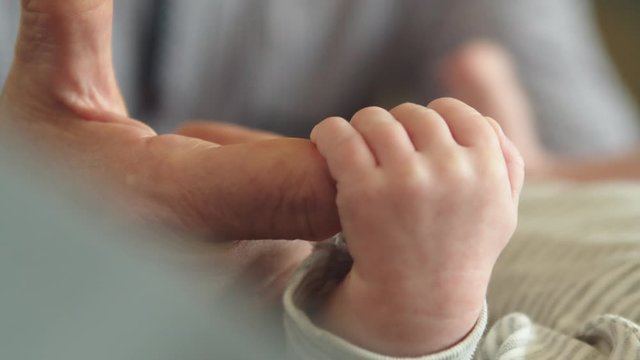 Little tinny newborn baby holding finger of the granny. Grandparenting, bonding, baby development and happy family concept