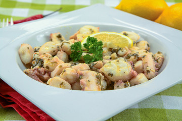 Octopus pieces cooked with garlic and parsley on a plate