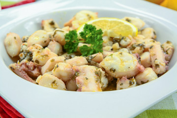 Octopus pieces cooked with garlic and parsley on a plate
