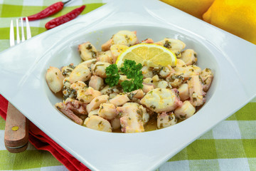 Octopus pieces cooked with garlic and parsley on a plate