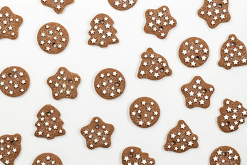 Pattern of ginger Christmas cookies on white background. Different shapes of cookies: Christmas tree, star, bell, circle. Top view, flat lay.