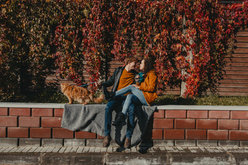 Young couple with a red cat on a background of an autumn city.